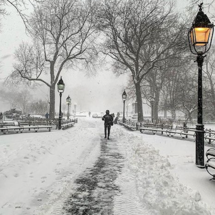 An almost empty, snow-covered path in Washington Square Park in winter